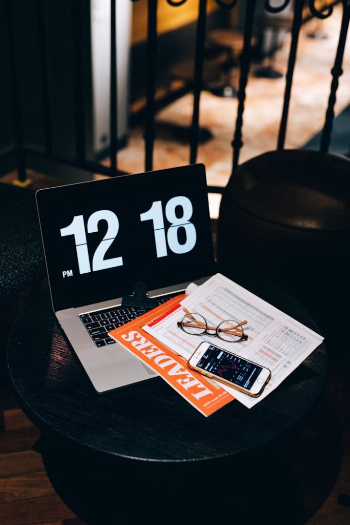 A sleek workspace featuring a laptop, smartphone, and documents on a round table, displaying business and finance themes.